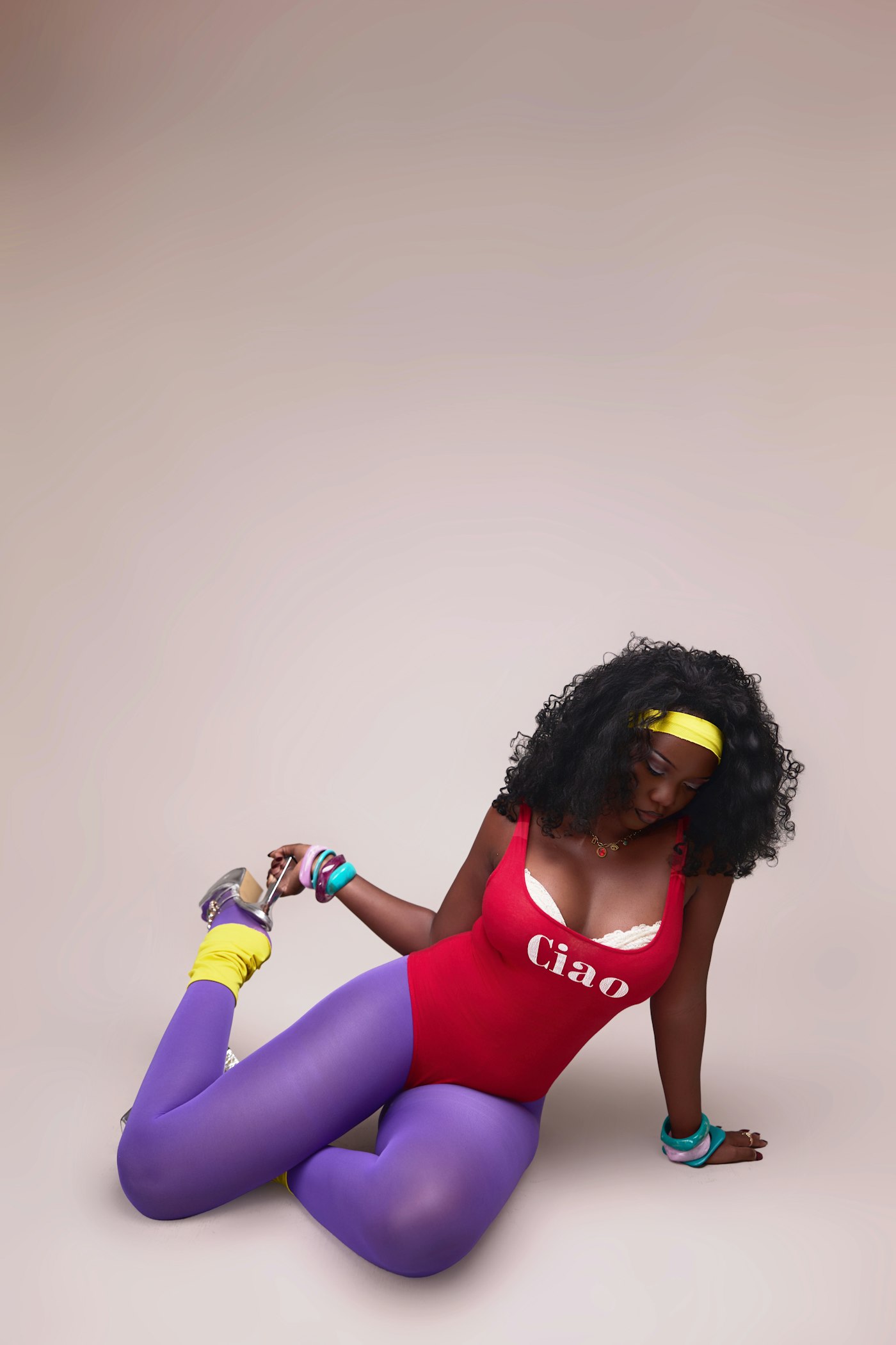 Woman in a red leotard, purple tights and a yellow headband, the classic 80s aerobics look